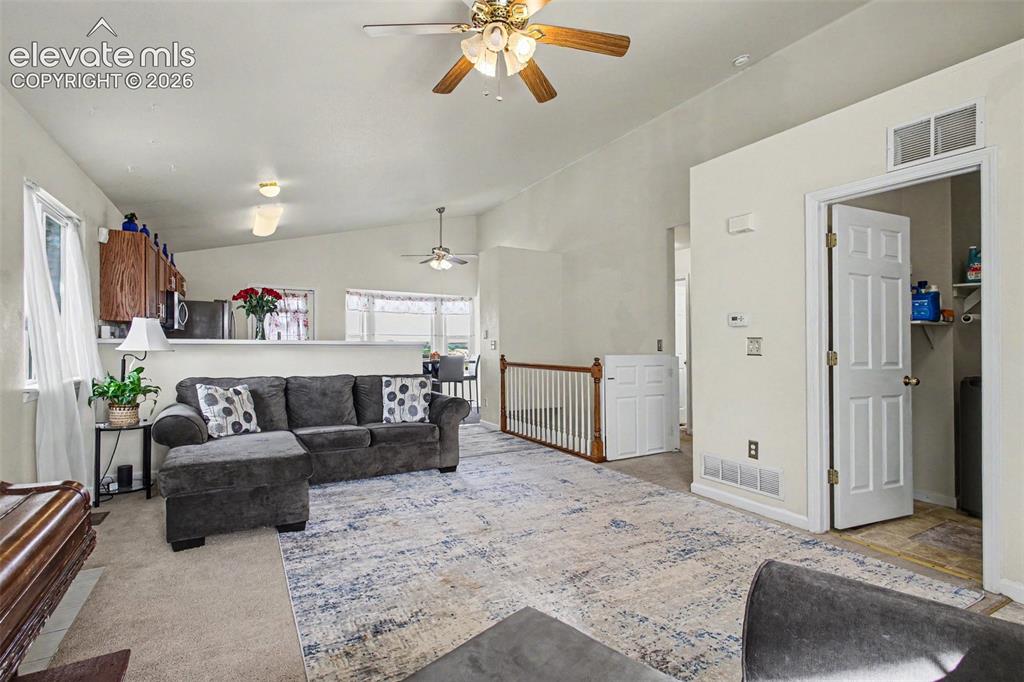 Image 5 of 33: Living area featuring vaulted ceilings, a ceiling fan, and carpeted floorin