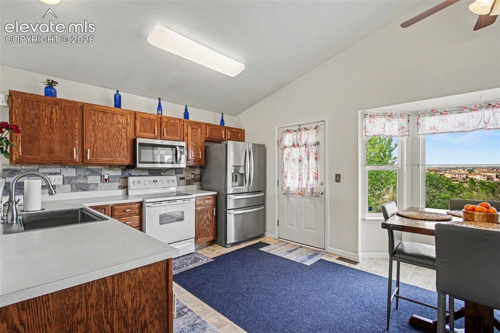 Image 9 of 33: Kitchen featuring wood cabinetry, stainless steel appliances, a tile backsp