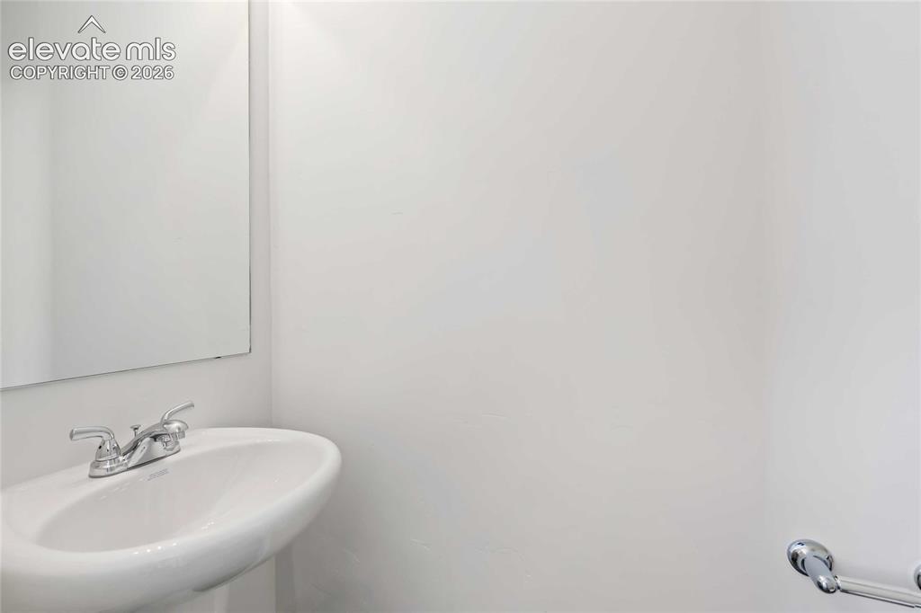 Image 10 of 25: White pedestal sink with chrome faucet and rectangular wall-mounted mirror