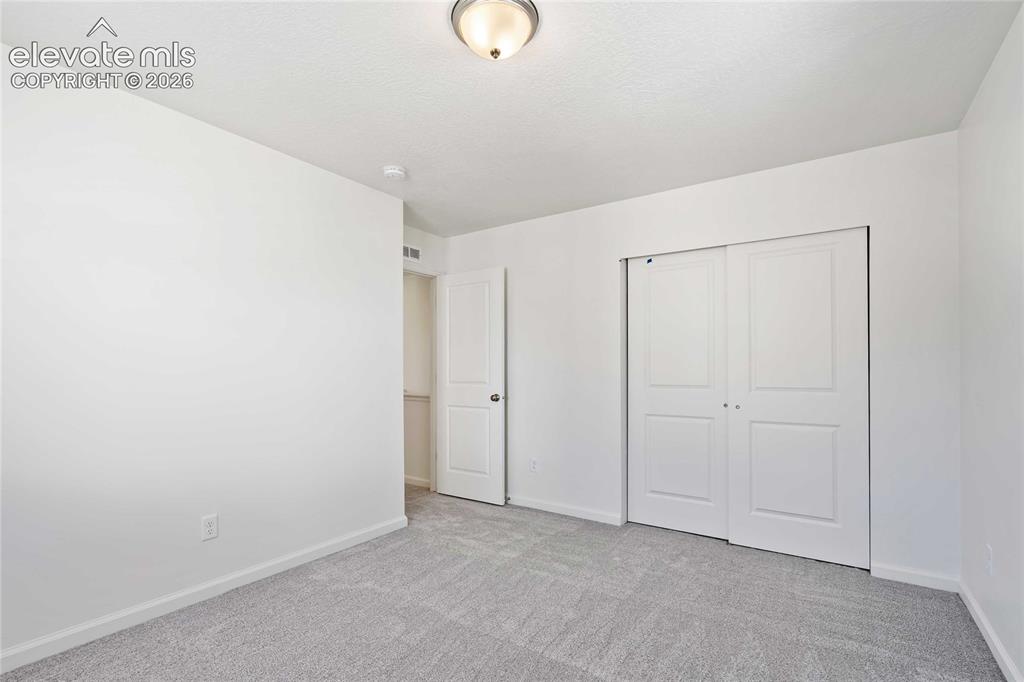 Image 20 of 25: Light gray carpeted flooring, white painted walls, and a ceiling-mounted li