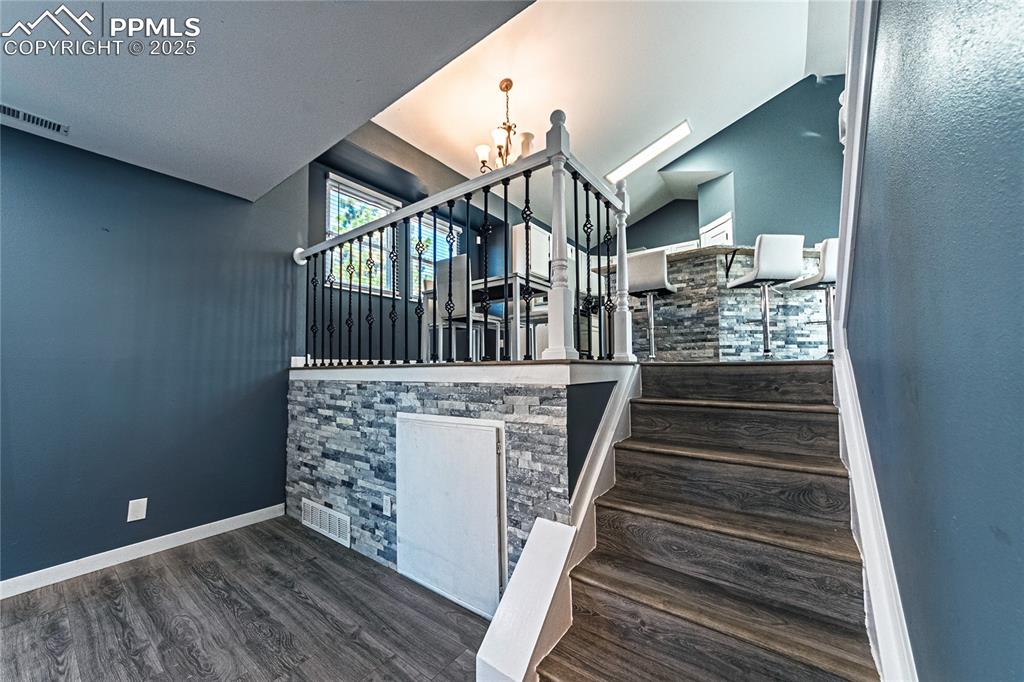 Image 11 of 46: Stairs with wood finished floors and a chandelier
