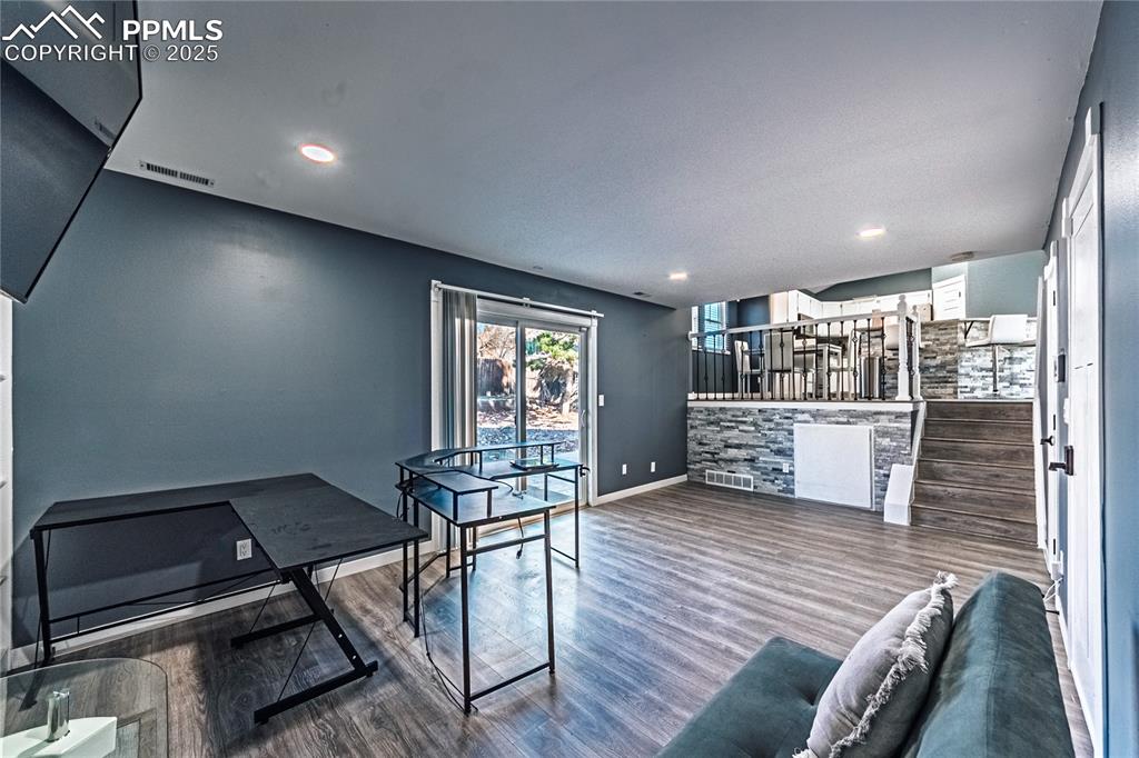 Image 14 of 46: Living area with wood finished floors, stairway, and recessed lighting