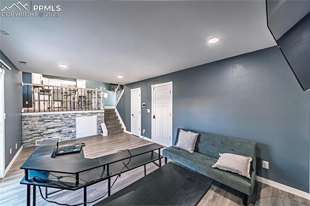 Image 15 of 46: Living area with wood finished floors, stairs, and recessed lighting