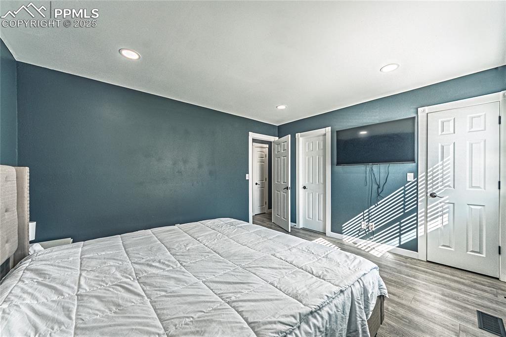 Image 23 of 46: Bedroom with wood finished floors, recessed lighting, and multiple closets