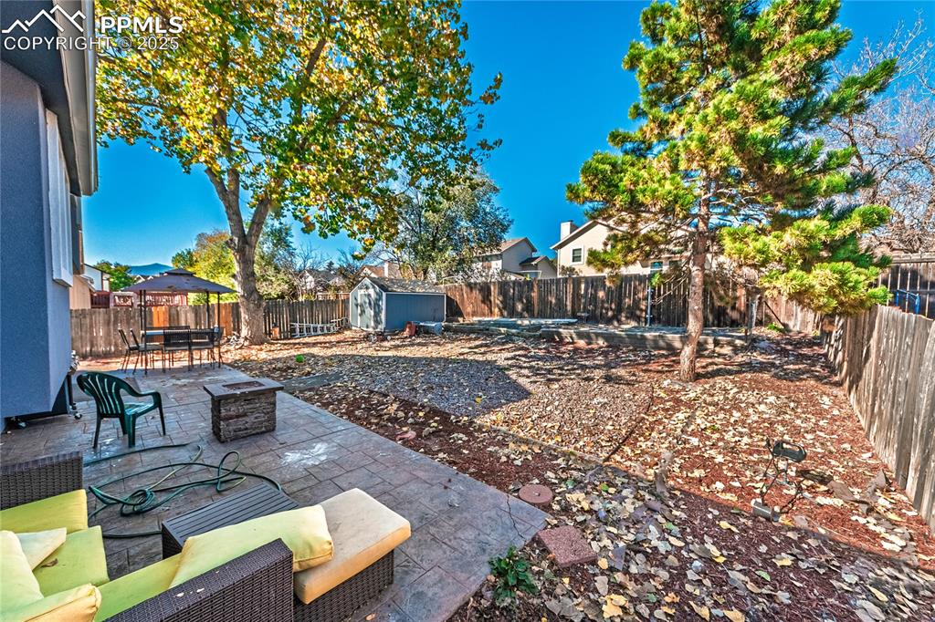 Image 26 of 46: Fenced backyard featuring a patio area, a storage shed, outdoor dining area
