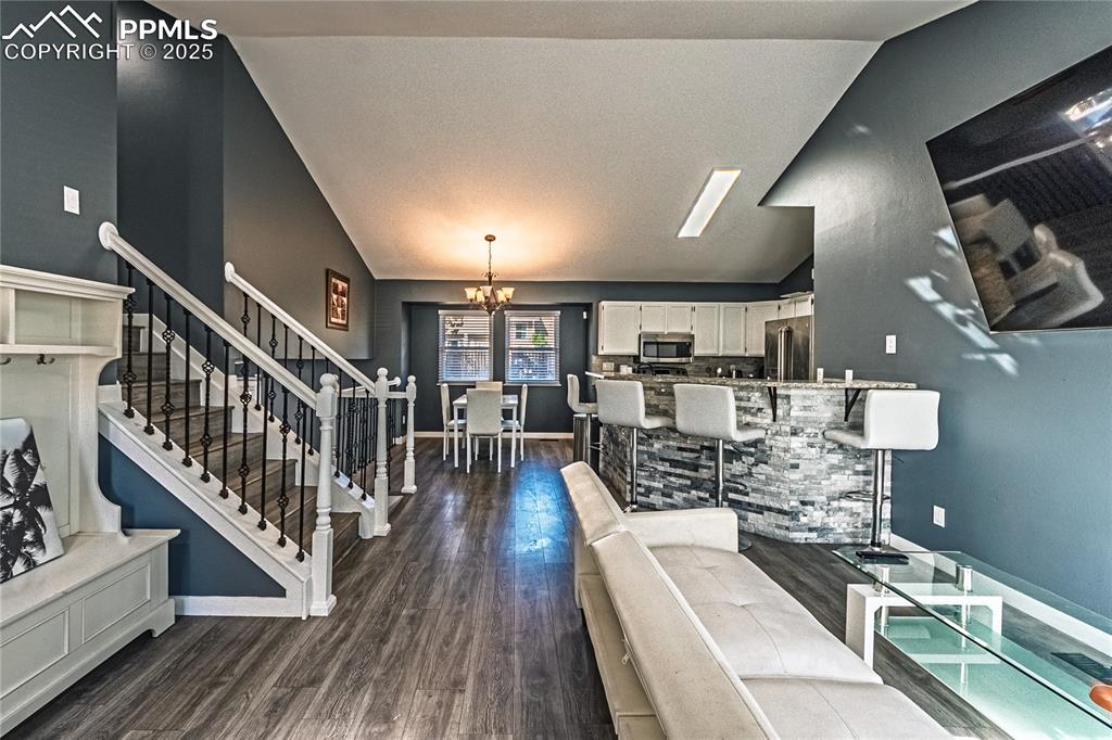 Image 5 of 46: Living room featuring a chandelier, dark wood-style flooring, stairway, and