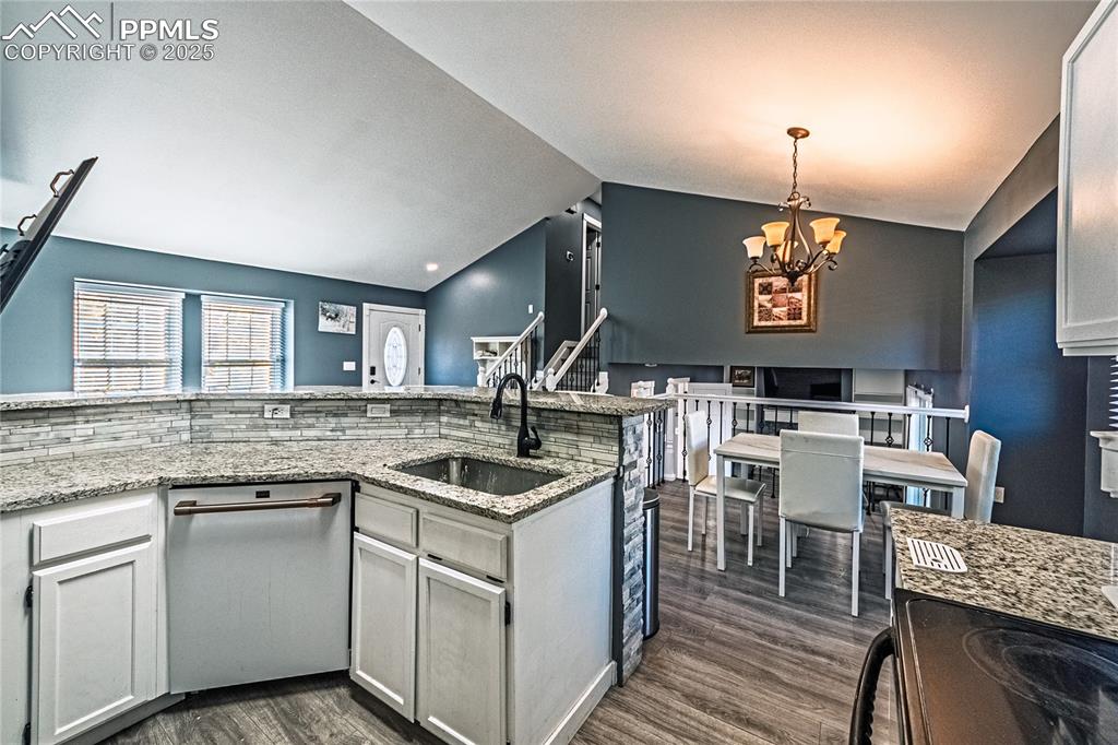 Image 7 of 46: Kitchen featuring electric range, white cabinets, light stone countertops,