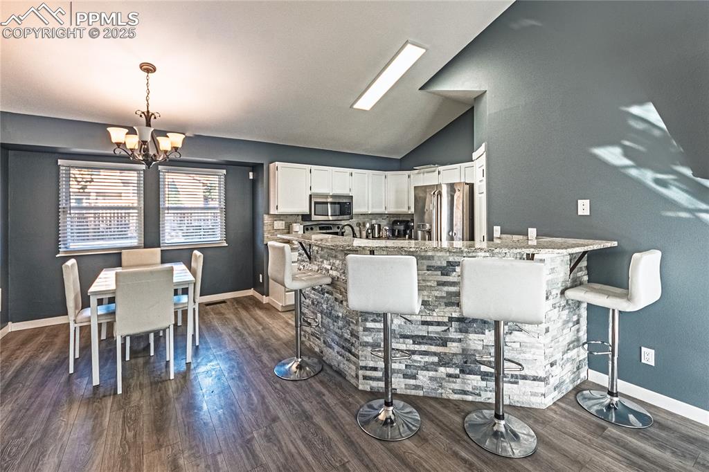 Image 8 of 46: Kitchen with white cabinets, a kitchen breakfast bar, pendant lighting, lof