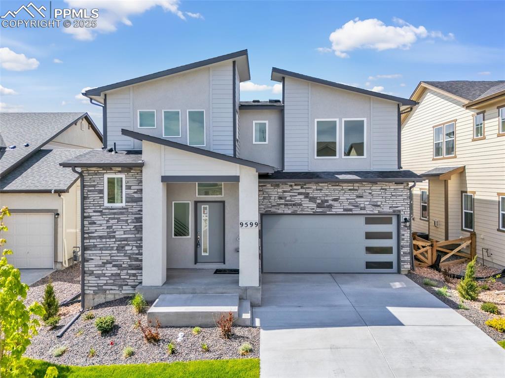 Caption: Contemporary house featuring stone siding, concrete driveway, a garage, a porch, and stucco siding