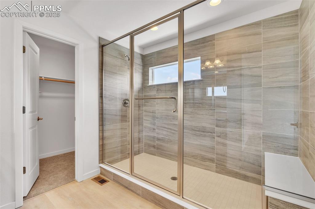 Image 11 of 43: Full bathroom with a shower stall, a walk in closet, light wood-type floori