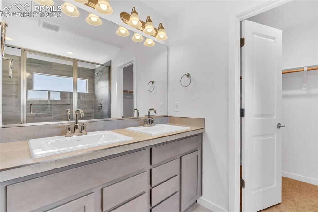 Image 12 of 43: Bathroom with a spacious closet, a stall shower, and double vanity
