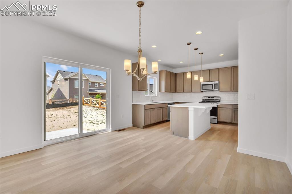 Image 26 of 43: Kitchen featuring a kitchen breakfast bar, a chandelier, stainless steel ap
