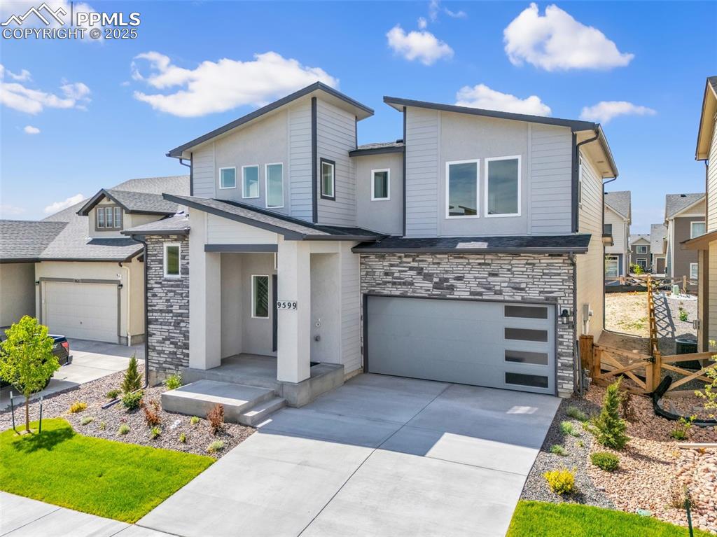 Image 3 of 43: Contemporary house with stone siding, driveway, a garage, and a shingled ro