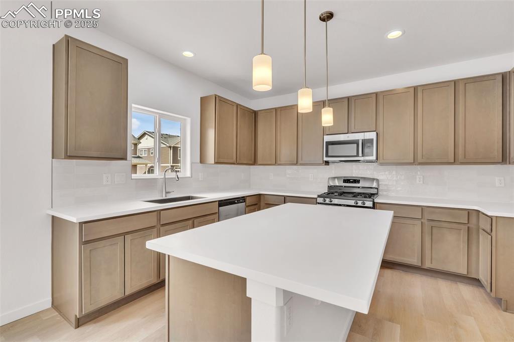 Image 31 of 43: Kitchen featuring decorative light fixtures, backsplash, stainless steel ap