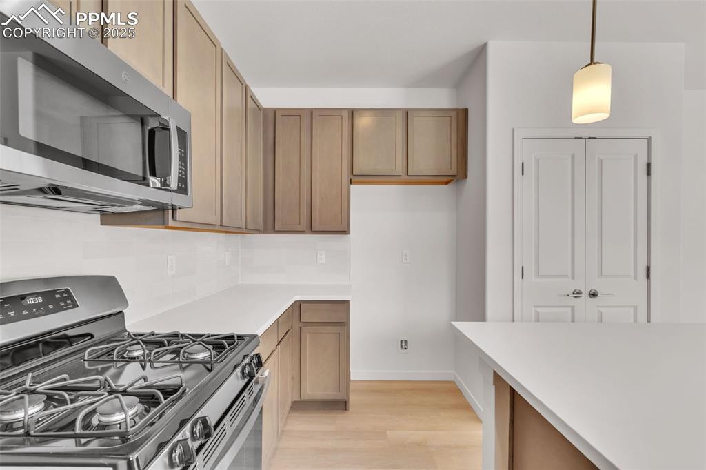 Image 34 of 43: Kitchen with stainless steel appliances, pendant lighting, light wood finis