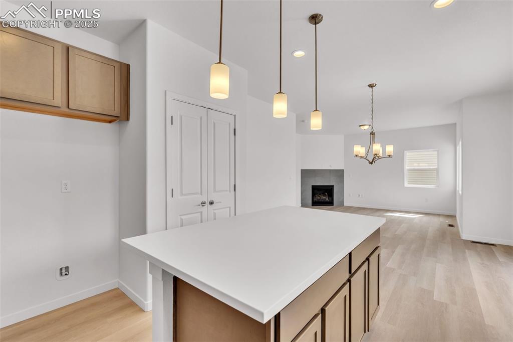 Image 36 of 43: Kitchen with a center island, decorative light fixtures, a fireplace, light