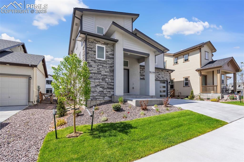 Image 4 of 43: View of front facade with stone siding, a front yard, driveway, and a garag