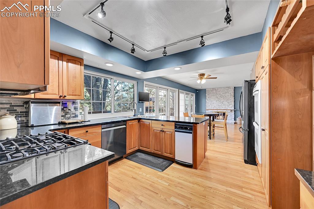 Image 11 of 43: Kitchen with light wood-style flooring, stainless steel appliances, dark st