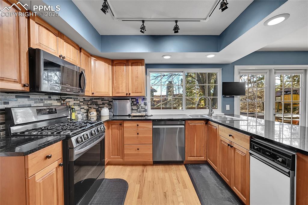 Image 12 of 43: Kitchen with stainless steel appliances, light wood-style floors, rail ligh
