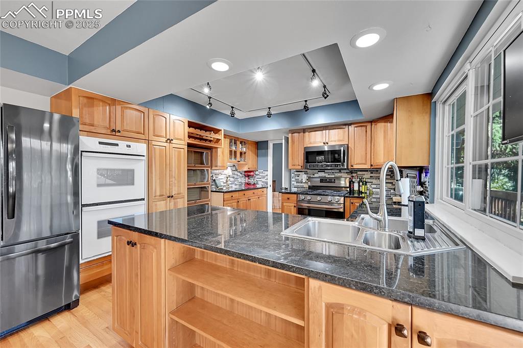 Image 14 of 43: Kitchen with open shelves, appliances with stainless steel finishes, rail l