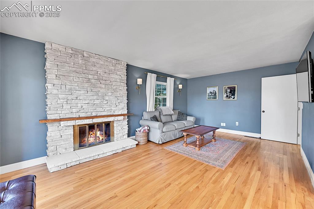 Image 18 of 43: Living room with light wood-type flooring and a stone fireplace