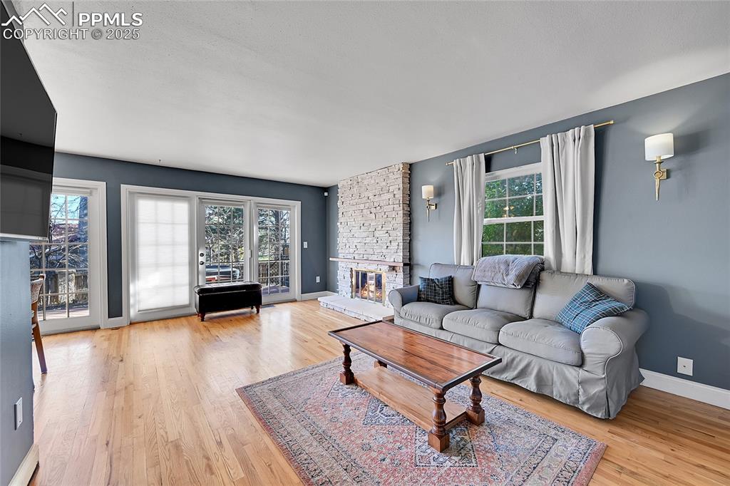 Image 19 of 43: Living area featuring a stone fireplace and light wood-type flooring