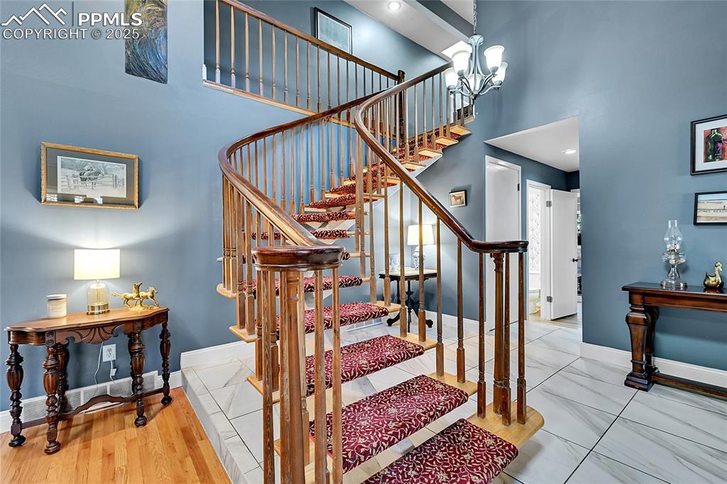 Image 21 of 43: Staircase featuring a high ceiling and a chandelier