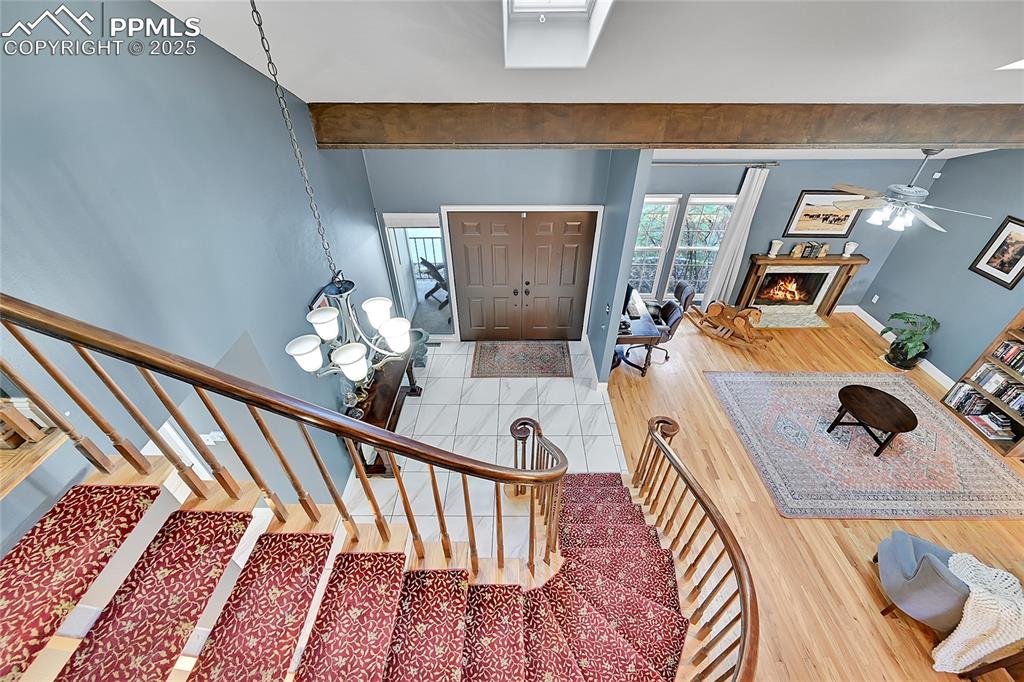 Image 22 of 43: Foyer entrance with beamed ceiling, wood finished floors, stairs, a chandel