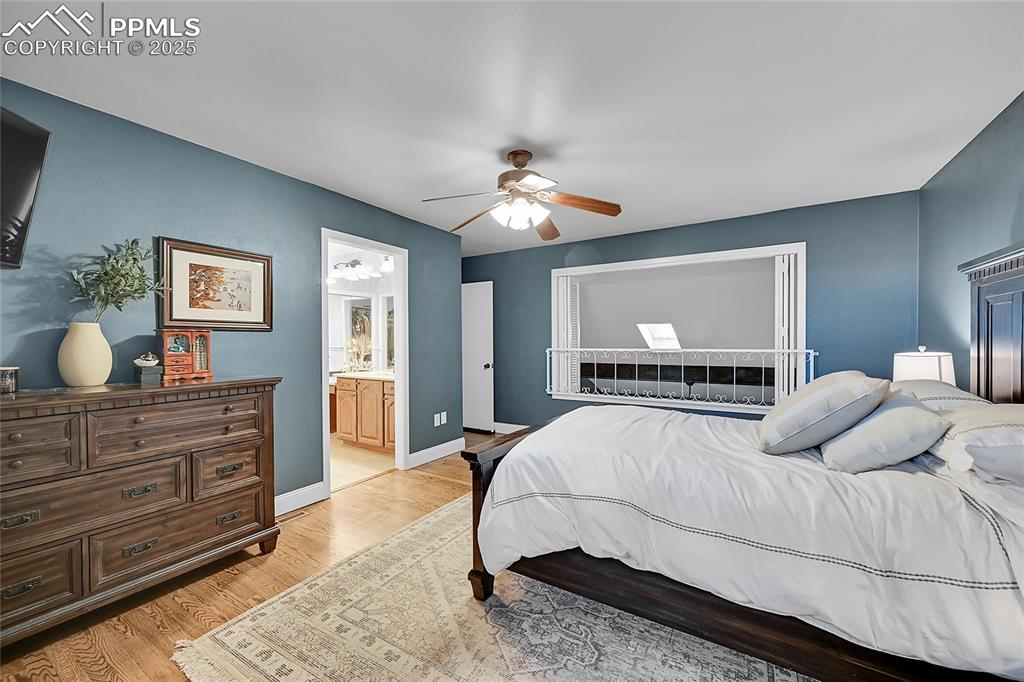 Image 25 of 43: Bedroom featuring light wood-style floors, a ceiling fan, and ensuite bathr