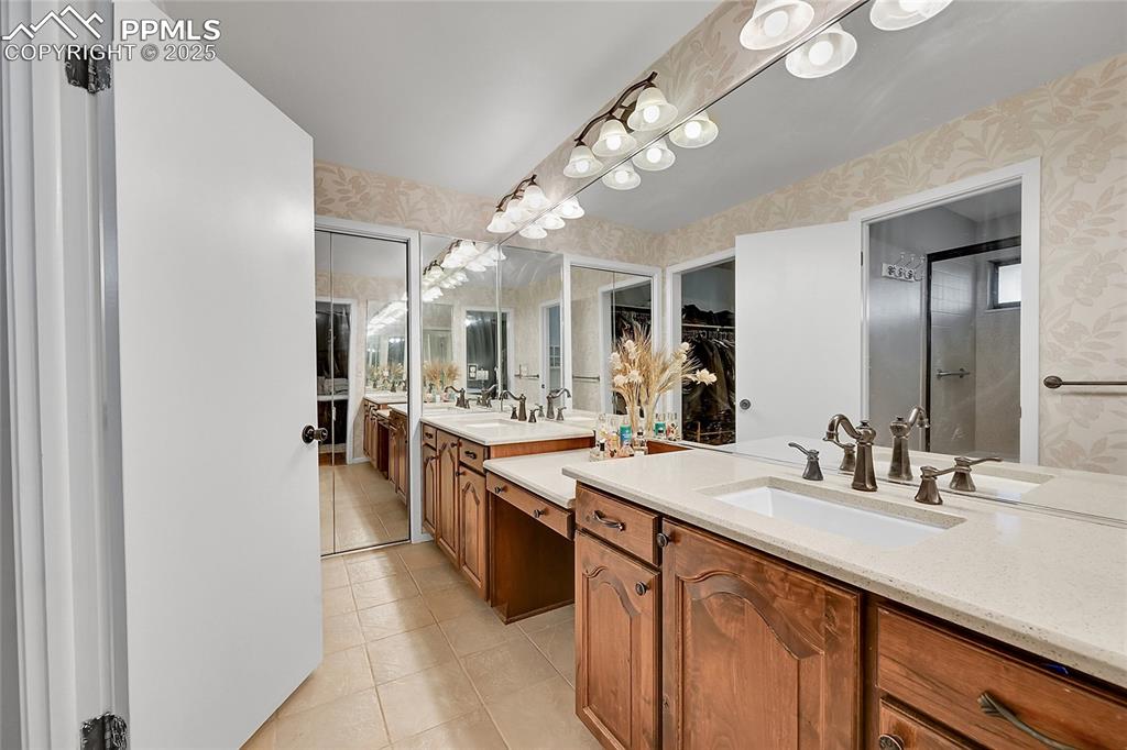 Image 27 of 43: Full bathroom featuring wallpapered walls, double vanity, and light tile pa