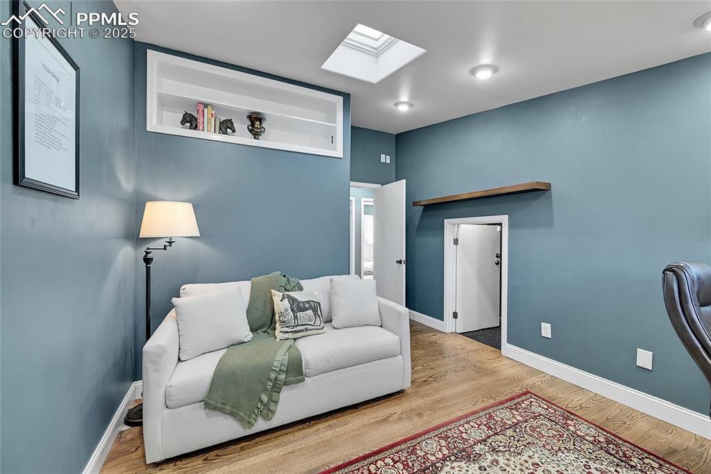 Image 34 of 43: Living area with a skylight and wood finished floors