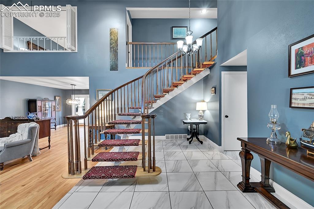Image 4 of 43: Stairs featuring a chandelier and a high ceiling