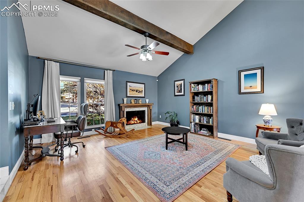 Image 5 of 43: Living area featuring an office area, a high end fireplace, beamed ceiling,