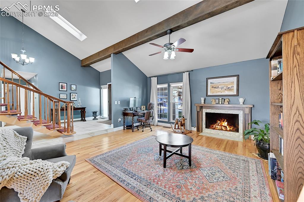 Image 6 of 43: Living area with a high end fireplace, high vaulted ceiling, light wood-sty