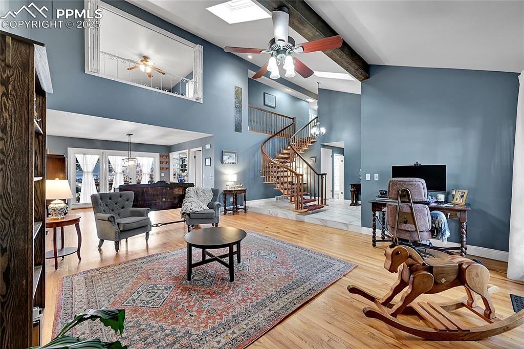 Image 7 of 43: Living room with wood finished floors, ceiling fan, stairway, a desk, and b