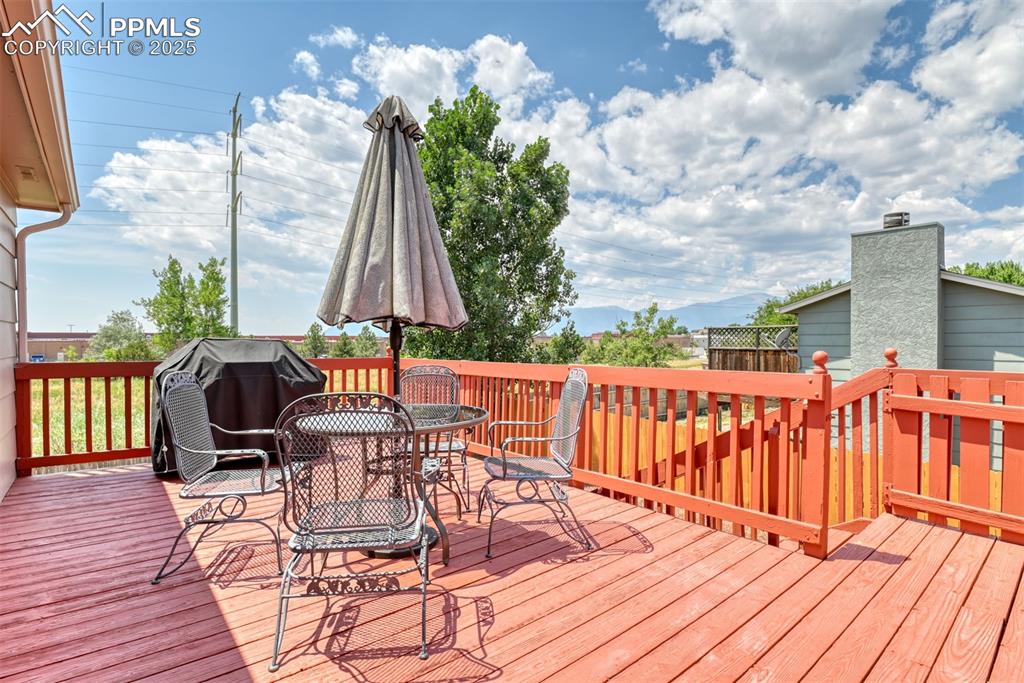 Image 17 of 46: Wooden deck featuring outdoor dining space and grilling area