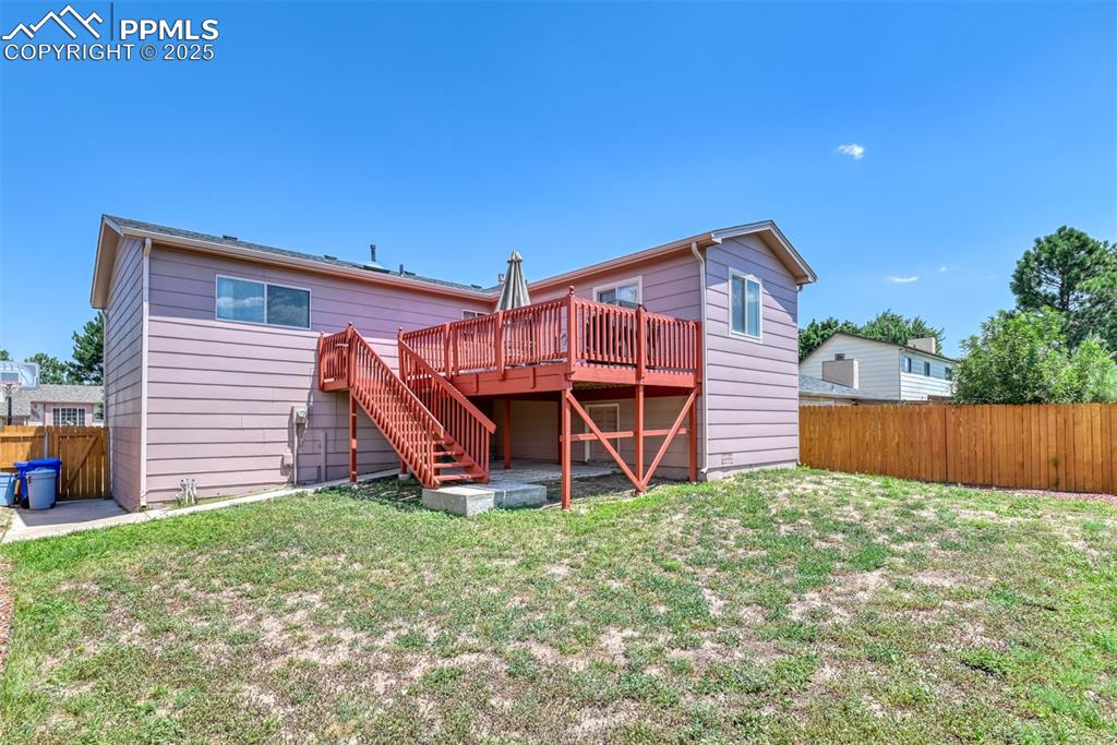 Image 20 of 46: Rear view of house featuring stairs and a wooden deck