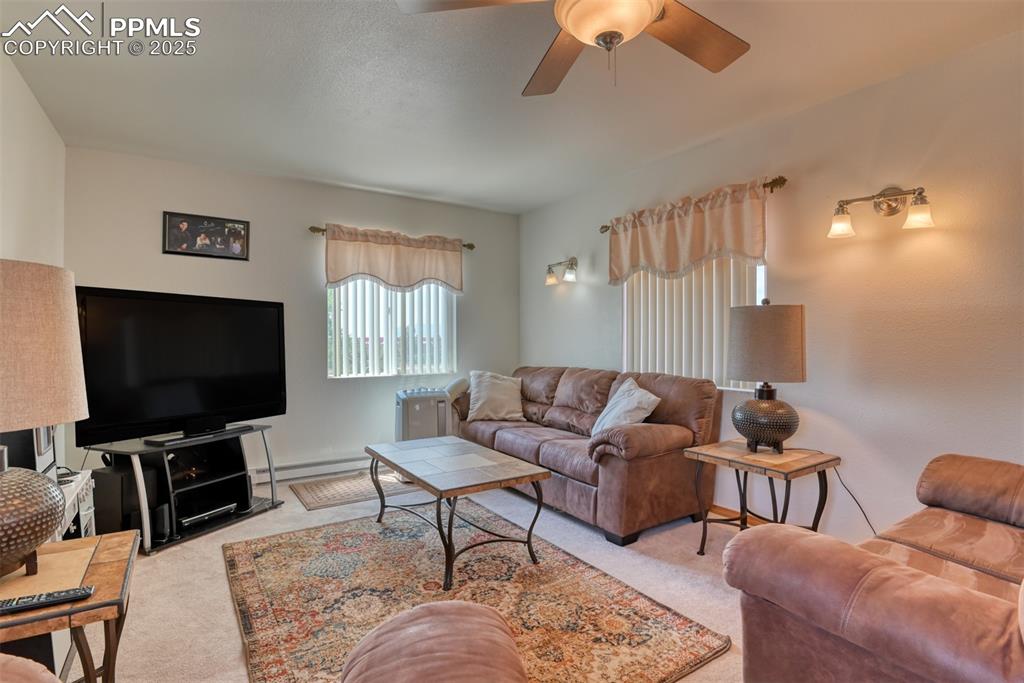 Image 26 of 46: Living room featuring carpet floors, a ceiling fan, and a baseboard heating