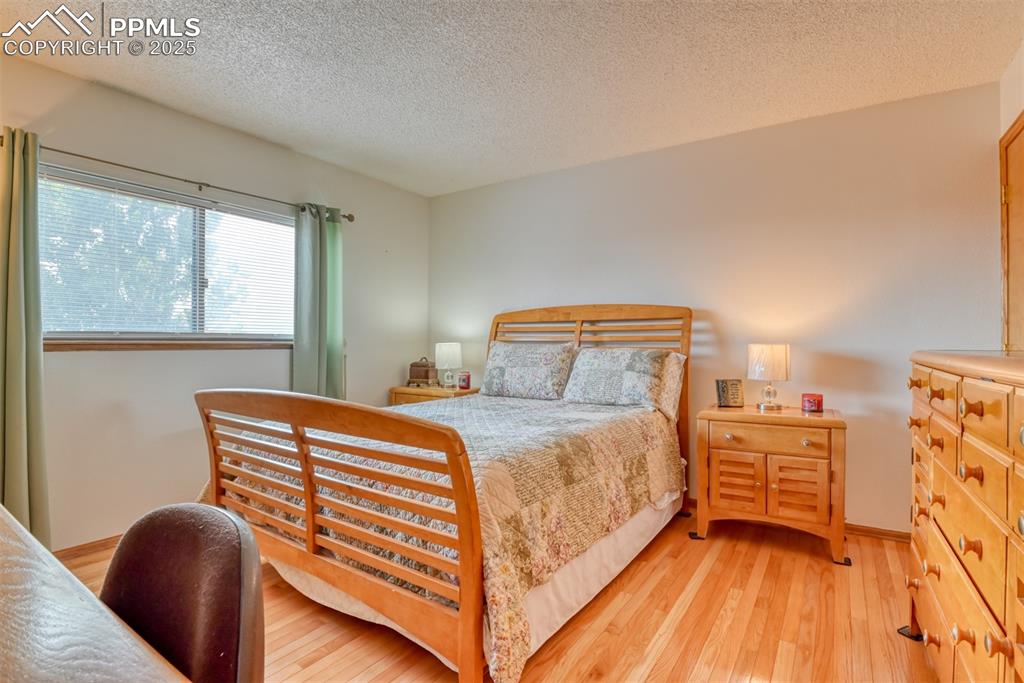 Image 29 of 46: Bedroom featuring light wood-type flooring and a textured ceiling