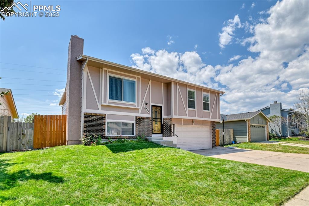 Image 3 of 46: Raised ranch with brick siding, stucco siding, concrete driveway, a chimney