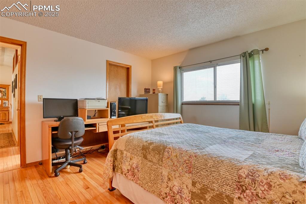Image 30 of 46: Bedroom with wood-type flooring, a textured ceiling, and an office area