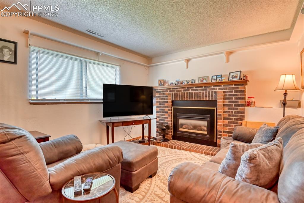 Image 40 of 46: Living room featuring a textured ceiling and a fireplace