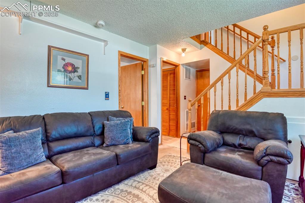 Image 42 of 46: Living area with stairs and a textured ceiling