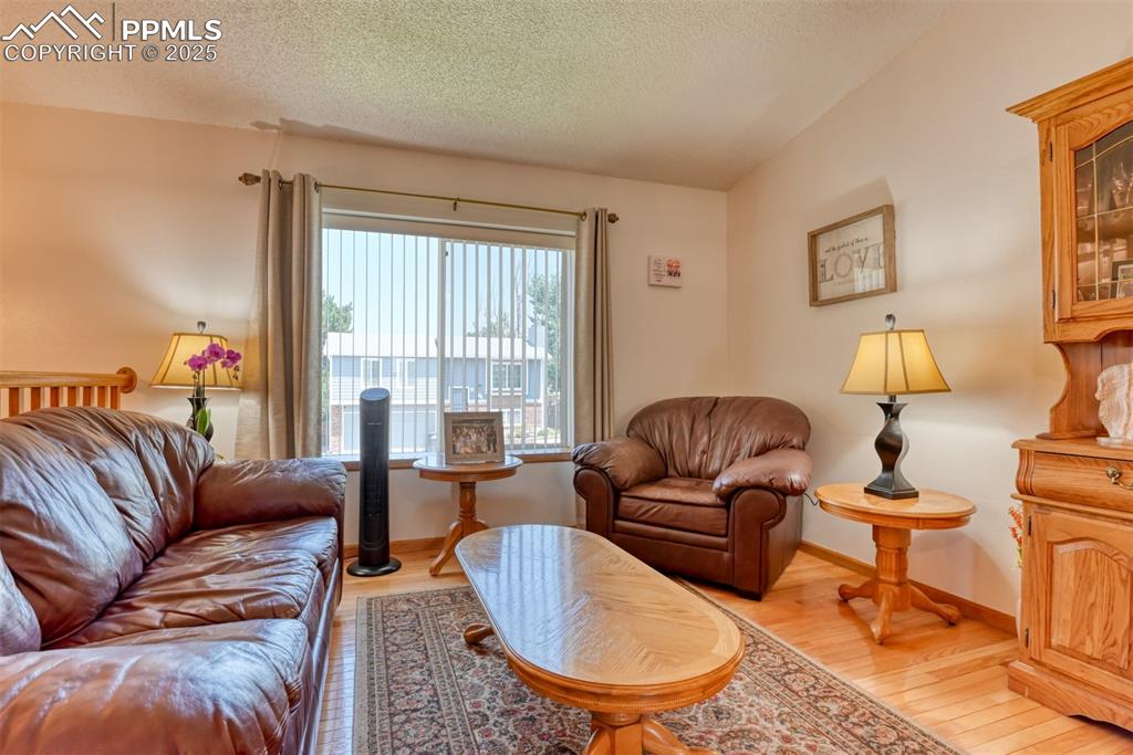 Image 7 of 46: Living area with light wood-style floors and a textured ceiling