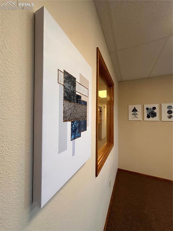 Image 12 of 45: Corridor featuring a paneled ceiling and carpet flooring