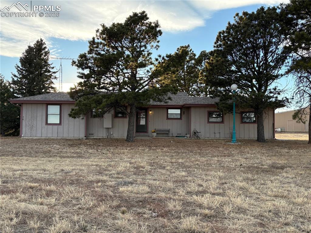 Caption: Ranch-style house with roof with shingles, a front yard, and board and batten siding