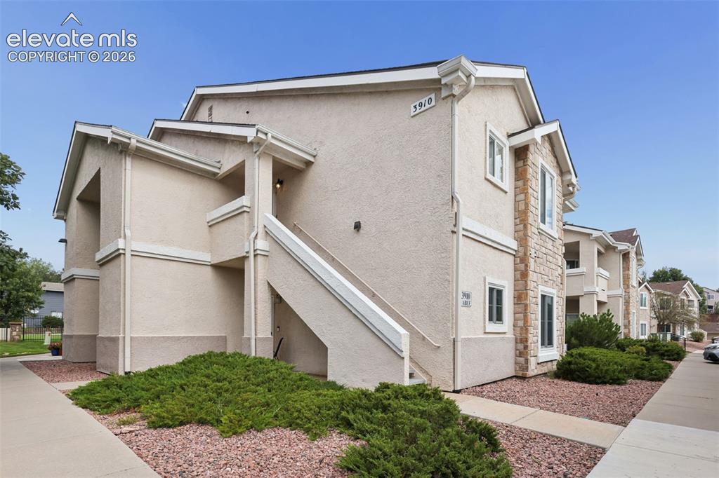 Caption: Multi-level building exterior featuring stucco siding, stone facade accents, multiple windows, an ex