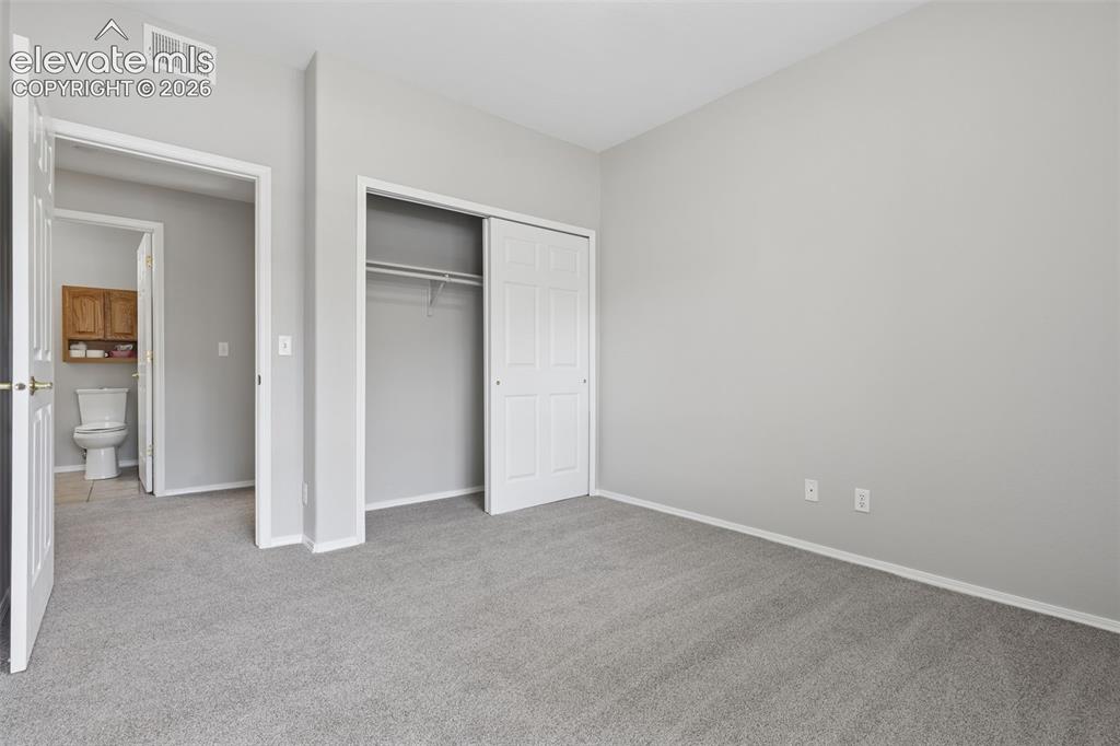 Image 21 of 27: Neutral-toned wall paint, gray carpeting, white trim, and a built-in closet