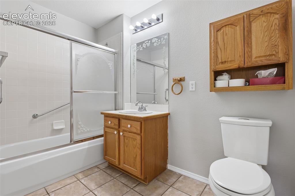 Image 22 of 27: Bathtub with sliding glass doors, white tiled surround, and grab bar