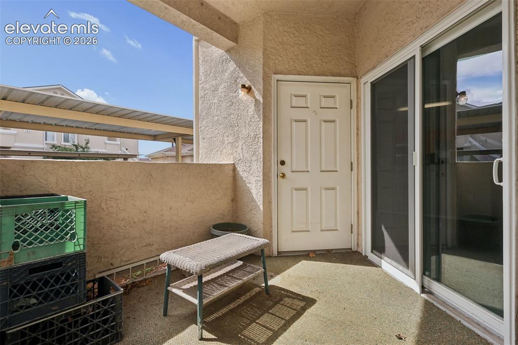 Image 24 of 27: Outdoor patio featuring a stucco exterior, privacy wall, and sliding glass